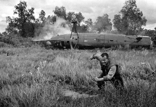 A crewman runs from a crashed CH-21 Shawnee troop helicopter near the village of Ca Mau in the southern tip of South Vietnam on December 11, 1962