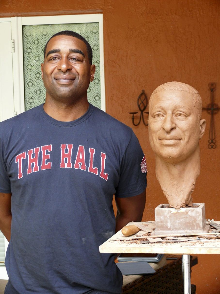 Cris Carter poses next to an early version of his Canton bust.