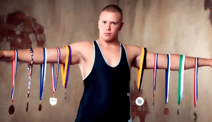 Pat Elflein posing with his high school wrestling photos / Elflein family photo