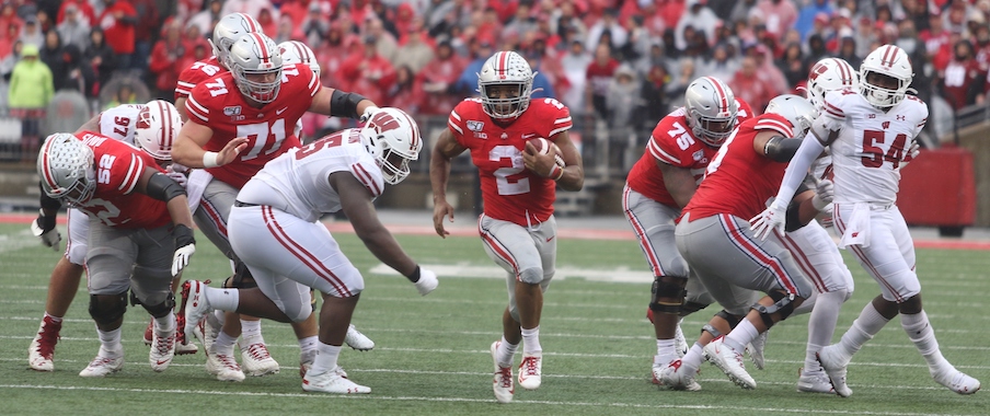 J.K. Dobbins running through a hole opened by his offensive line