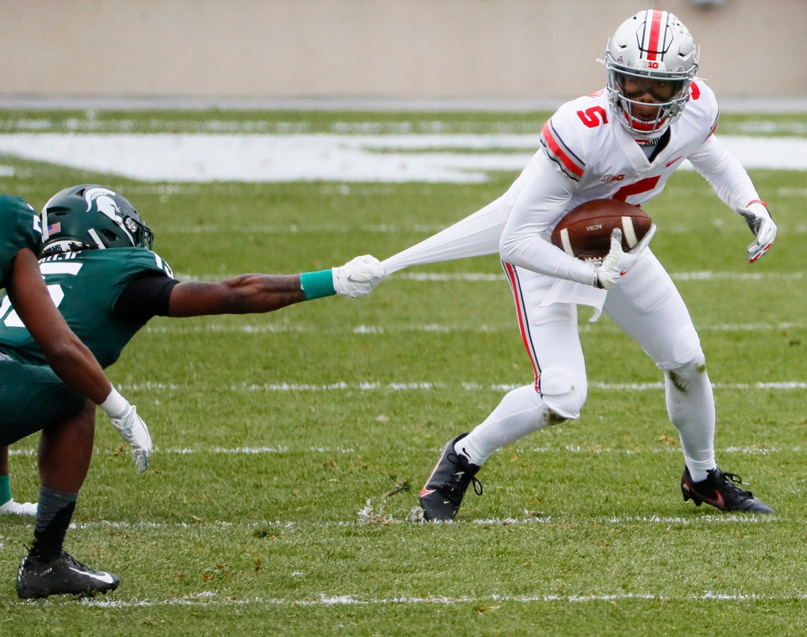 Ohio State Buckeyes wide receiver Garrett Wilson (5) works to break a tackle from Michigan State Spartans cornerback Angelo Grose (15) during the second quarter of a NCAA Division I football game between the Michigan State Spartans and the Ohio State Buckeyes on Saturday, Dec. 5, 2020 at Spartan Stadium in East Lansing, Michigan. Cfb Ohio State Buckeyes At Michigan State Spartans