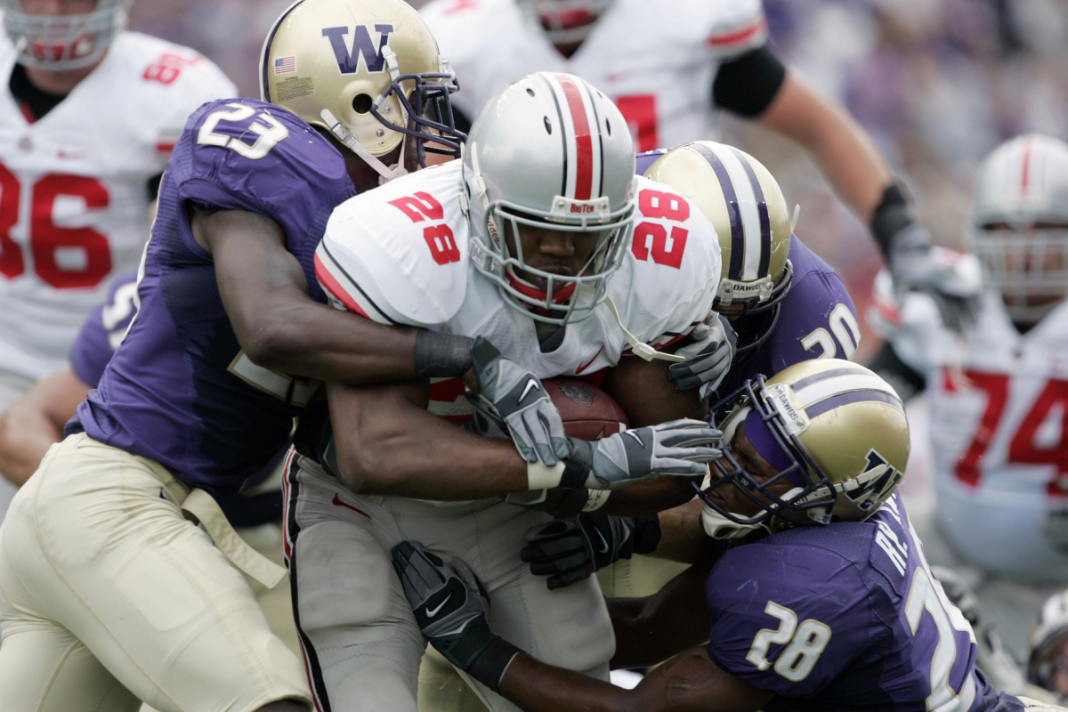 Sept 15, 2007; Seattle, WA, USA; Ohio State Buckeye tail back Chris Wells (28) is tackled by Washington Husky safety Mesphin Forrester (23) cornerback Roy Lewis (28) and linebacker Kyle Trew (20) in the first half of the Buckeyes' 33-14 victory at Husky Stadium. Mandatory Credit: Joe Nicholson-Imagn Images