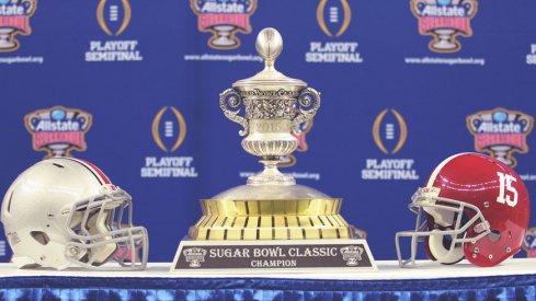Ohio State and Alabama helmets next to the 2015 Sugar Bowl trophy.