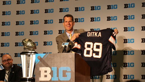 Jim Harbaugh holds up a Mike Ditka jersey.