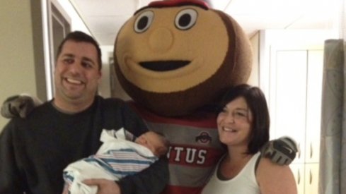 Corey, his son Zade, and wife, Amber, pose with Brutus Buckeye
