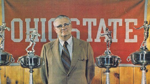 Hayes poses with a small sampling of his hardware for the 1976 Michigan game program cover.