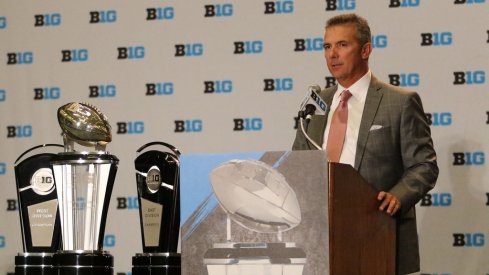 Ohio State coach Urban Meyer stands next to the trophies the Big Ten will be competing for this year.