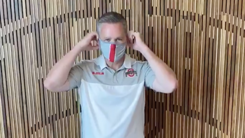 Chris Holtmann puts on a mask.