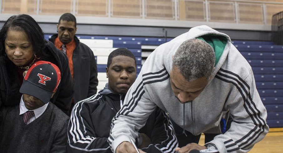Greg McDowell, father of Michigan State football commit Malik McDowell, signs paperwork at his son's national signing day press conference at Southfield High School on Wednesday. It's not known what documents were signed, but the Spartans have yet to receive a signed national letter of intent or Big Ten tender document. (Katie Bailey l MLive.com)