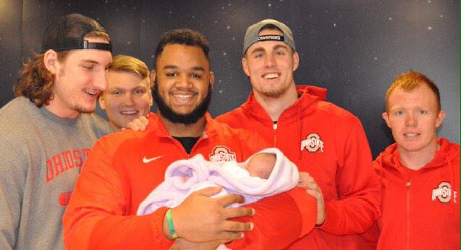 Ohio State All-American defensive tackle Michael Bennett holds a three-week-old baby, Bayah, at Nationwide Chilrden's Hospital Friday.