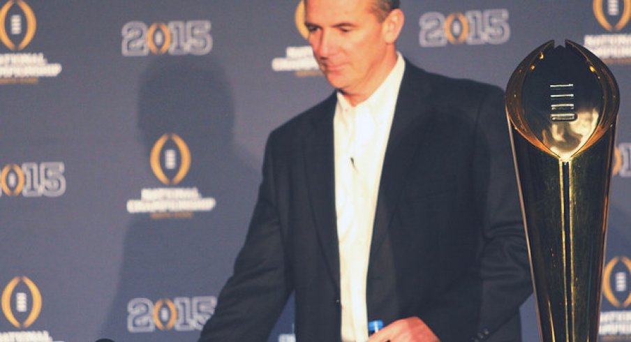 Urban Meyer standing next to the National Championship trophy