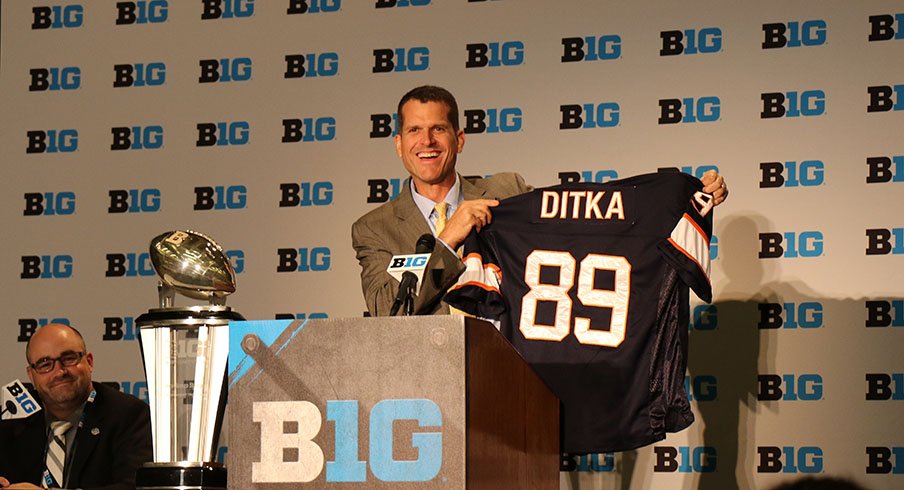Jim Harbaugh holds up a Mike Ditka jersey.