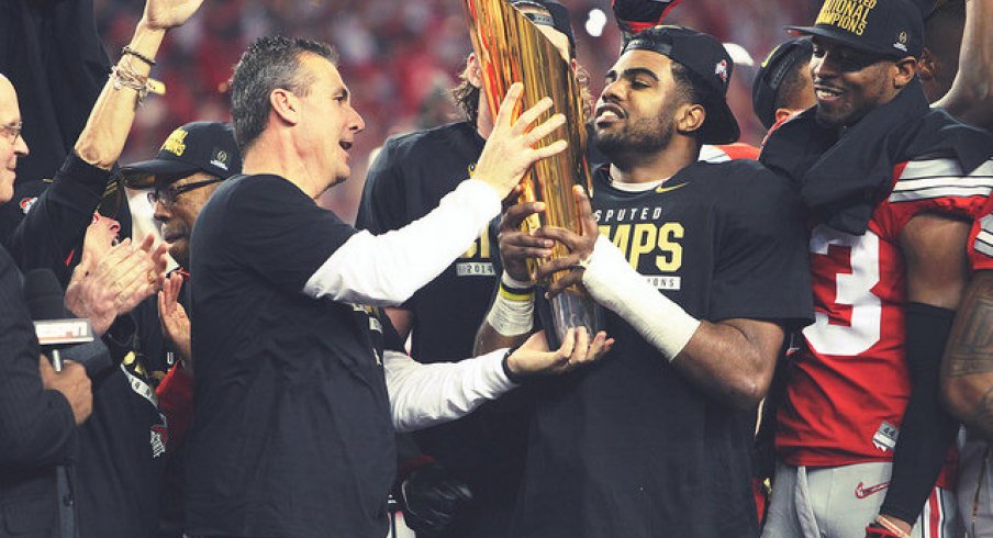 Urban Meyer and Ezekiel Elliott holding the world's first CFP trophy.