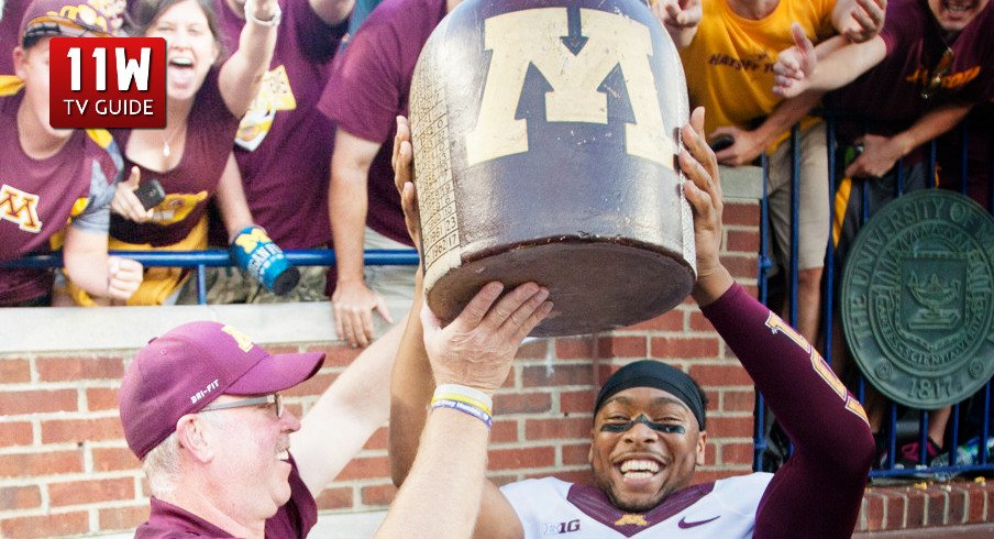 27 September 2014: Minnesota head coach Jerry Kill, left, and defensive back Cedric Thompson (2) lift up and celebrate with the Little Brown Jug trophy, after an NCAA college football game between the Michigan Wolverines and Minnesota, at Michigan Stadium in Ann Arbor, Michigan.