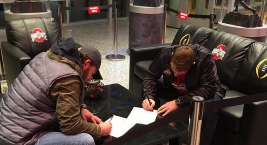 Craig Fada and Joe Burger sign their scholarship deals.