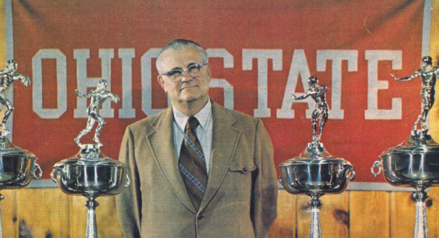 Hayes poses with a small sampling of his hardware for the 1976 Michigan game program cover.