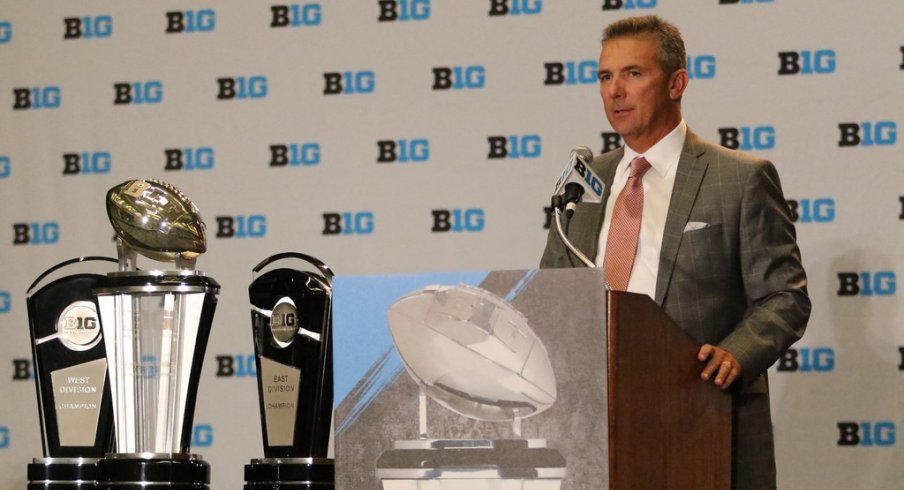 Ohio State coach Urban Meyer stands next to the trophies the Big Ten will be competing for this year.