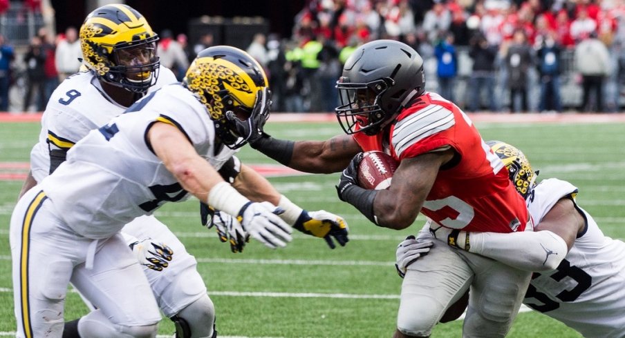Nov 26, 2016; Columbus, OH, USA; Ohio State Buckeyes running back Mike Weber (25) tries to get past Michigan Wolverines defensive end Taco Charlton (33) and linebacker Ben Gedeon (42) at Ohio Stadium. Ohio State won the game 30-27 in double overtime.