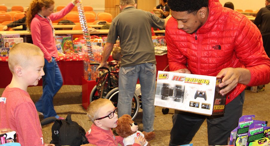 Malik Harrison helps a child pick out a toy during the Buckeyes' visit to the Nationwide Children's Hospital on Monday.