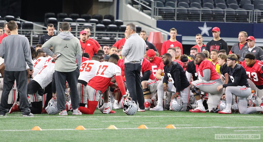 Urban Meyer calls a huddle before the Buckeyes begin practice at AT&T Stadium on Tuesday.