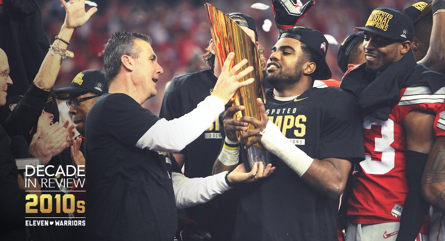 Urban Meyer hands the national championship trophy for the 2014 season to Ezekiel Elliott.