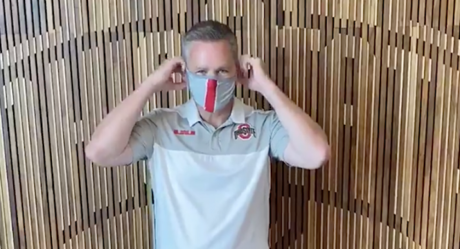 Chris Holtmann puts on a mask.