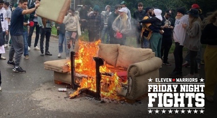 A small crowd gathers as a couch is burned on Harrison Road near Elm Street in East Lansing on Saturday, Oct. 30, 2021, after Michigan State's 37-33 football victory over Michigan.