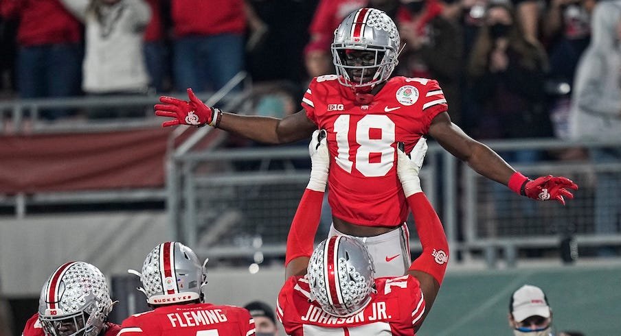 Paris Johnson Jr. hoisting Marvin Harrison Jr. up in the air