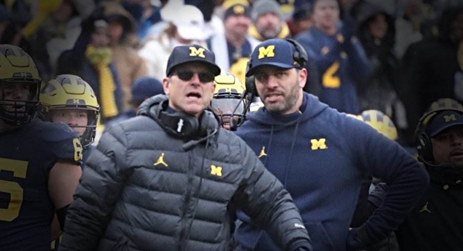 Michigan Wolverines head coach Jim Harbaugh, center, speaks with quarterbacks coach Matt Weiss, right, during action against the Ohio State Buckeyes on Saturday, Nov. 27, 2021 at Michigan Stadium.