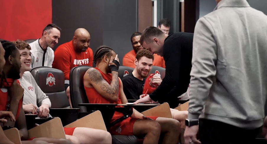 Jake Diebler signing his contract in front of the team